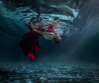Girl in red dress floating underwater