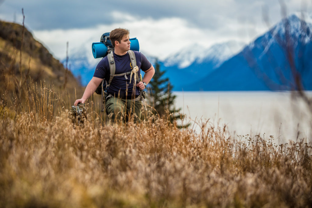 High school senior boy hiking, with a backpack in the mountains