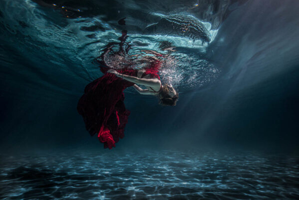 Girl in red dress floating underwater