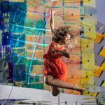 Alysa-0522-copy girl in a orange dress jumping in front of a sculpture