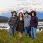 DeLeon Family 2025-3911 family standing in a field with a mountain background