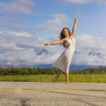 Isabella-Bogh-2420-copy girl standing on a road in a white dress with mountains in the back