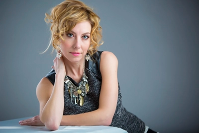 Mature blonde woman in an elegant outfit posing in a photography studio
