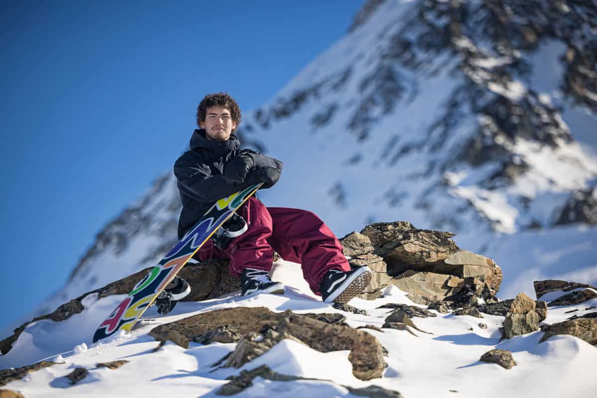 high school boy with a snowboard on a glacier