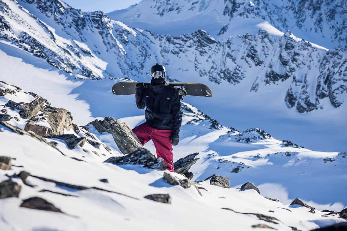 senior photo of a high school boy with a snowboard on a glacier