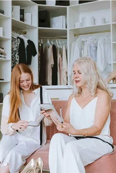 photo of two women seated and discussing clothing options