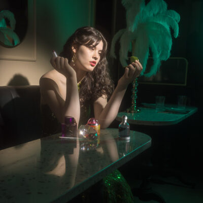 High School Senior Girl in glamouros retro style sitting in a restaurant with vintage noir lighting.