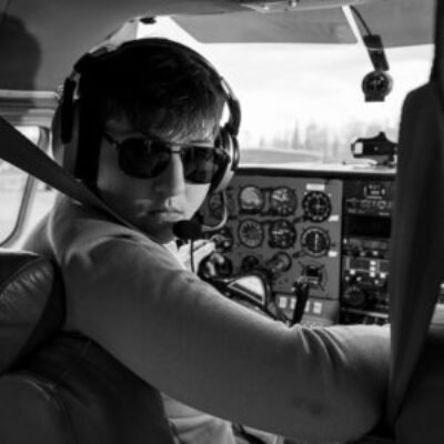 Black and white image a high school senior boy in the cockpit of a small airplane