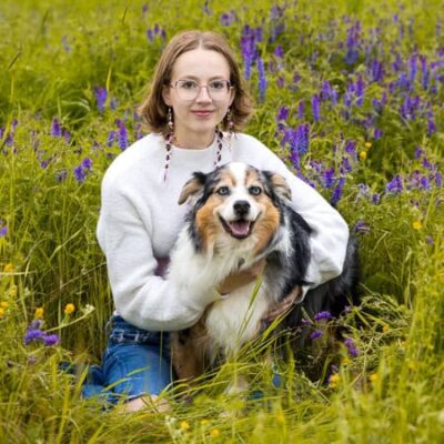 High school senior girls in a grassy field holding her dog