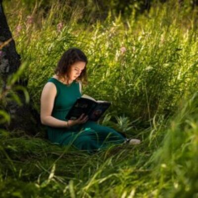 High school senior girl reading a book under a tree