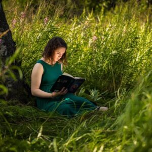 High school senior girl reading a book under a tree