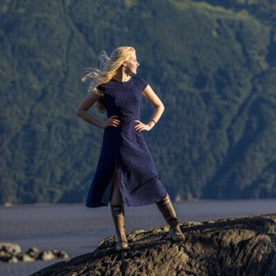 Long haired blonde Senior high school girl stading by water in the wind