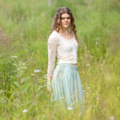 Soft focus of high school senior girl wearing a boho outfit in a grassy field