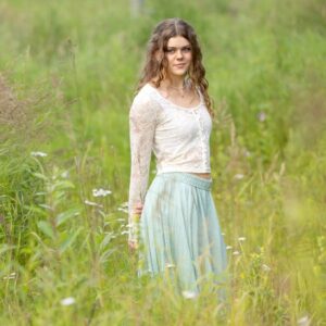 Soft focus of high school senior girl wearing a boho outfit in a grassy field
